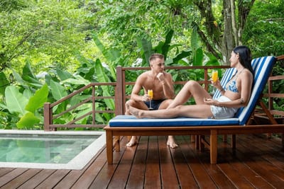 Couple relaxing in front of a pool at an eco-lodge in Costa Rica, surrounded by lush tropical greenery.