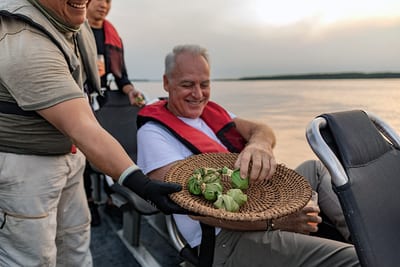 Travelers on a small skiff watch the sunset over the Amazon river during a guided tour, Brazil.