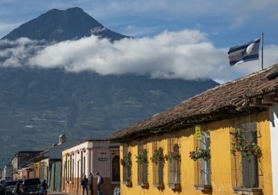A colonial street in Antigua Guatemala with a volcano rising beyond the rooftops.