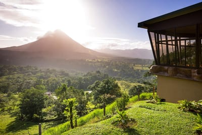 Arenal Volcano backlit by morning sun above green hills, Costa Rica