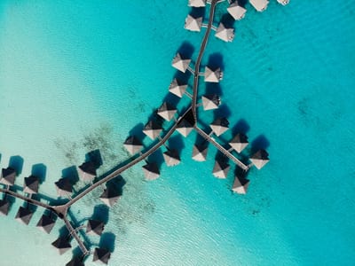 Aerial view of thatched overwater bungalows reaching into the turquoise shallows of the Belize Barrier Reef off San Pedro, Belize.