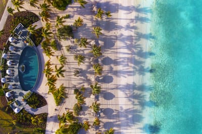 Sun loungers on a white-sand beach above a clear turquoise Caribbean bay.