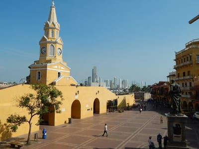Cartagena's yellow Torre del Reloj clock tower above a colonial plaza in the walled city, Colombia.