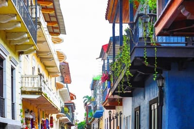 Colorful restored colonial townhouses with wrought-iron balconies and hanging plants on a quiet Casco Viejo street in Panama City.