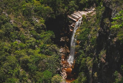 A waterfall drops through dense green forest in Chapada Diamantina National Park, Bahia, Brazil.