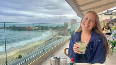 A woman enjoys a caipirinha on a balcony overlooking the beach in Rio de Janeiro, Brazil.