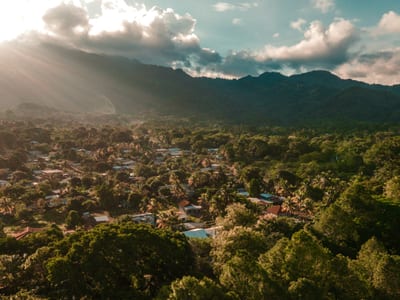 An aerial view of the town of Copán Ruinas nestled in a forested green valley below the western hills of Honduras at golden hour.