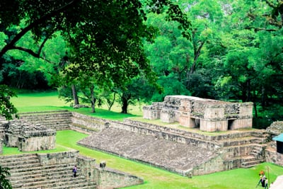 The grassy main plaza and weathered stone structures of the ancient Maya city of Copán, a UNESCO World Heritage Site in western Honduras.