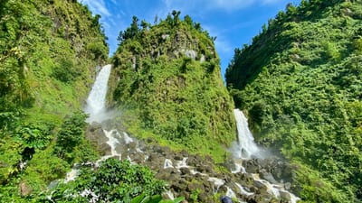 Twin waterfalls cascade through lush jungle on Dominica, Caribbean.