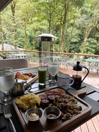 Breakfast tray with gallo pinto, eggs, fruit and a french press on the restaurant deck of El Silencio Lodge, overlooking the cloud forest