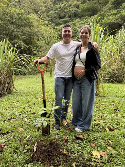 A couple on their babymoon planting an aguacatillo tree as part of the El Silencio Lodge reforestation initiative