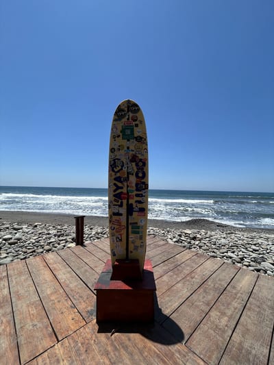 A surfboard rests on the volcanic black sand of El Tunco beach on El Salvador's Pacific surf coast.