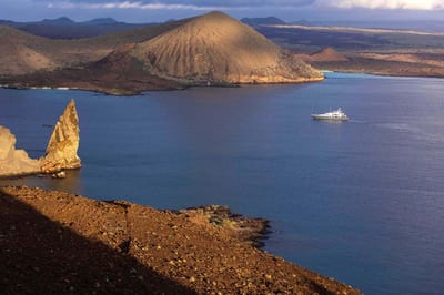 The iconic Pinnacle Rock and golden volcanic cones of Bartolomé Island rising above turquoise water in the Galápagos Islands, Ecuador.