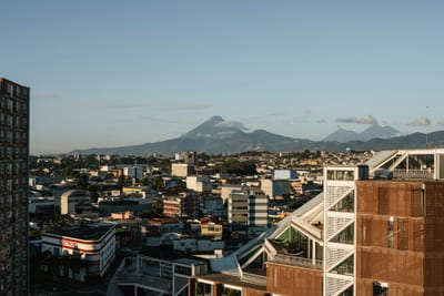 The cityscape of Guatemala City at golden hour with the volcano range rising on the horizon, Guatemala.