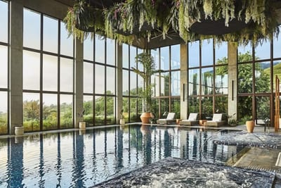 Indoor spa pool with a bubbling jacuzzi in the foreground and double-height windows onto the mountains at Hacienda AltaGracia in Pérez Zeledón, Costa Rica