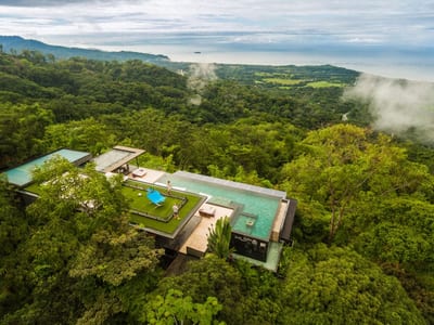 Aerial view of Kura Design Villas, its green roof and twin infinity pools set on a rainforest ridge above the Pacific in Uvita, Costa Rica