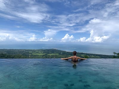 A woman in the clifftop infinity pool at Kura Design Villas overlooking the Pacific coast near Uvita, Costa Rica