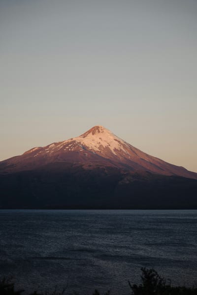 A snow-capped volcano rises above the forests and lakes of Chile's Lake District.