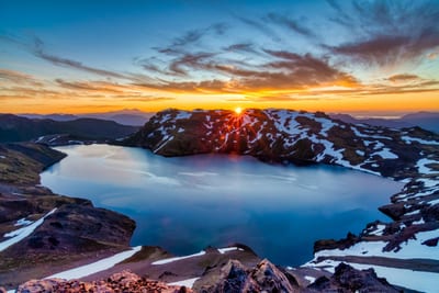 Sunset glows over a volcano and lake in Chile's Lake District.