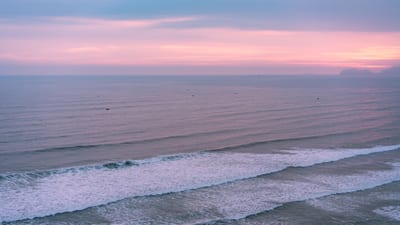 The sun setting over the Pacific Ocean beyond the Miraflores cliffs of Lima, Peru.