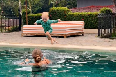 A mother reaches out to catch her young daughter mid-jump into a villa swimming pool, Costa Rica.
