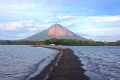 The cone of Concepción volcano on Ometepe Island rising beyond a natural sandbar reaching across Lake Nicaragua