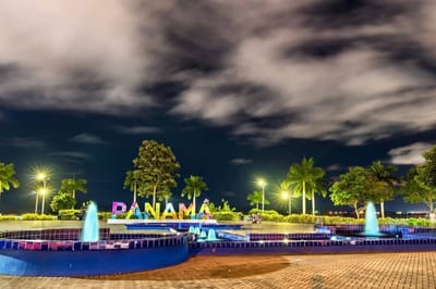 The illuminated multicolor PANAMA sign behind lit blue-tiled fountains and palm trees on the Amador Causeway waterfront at night