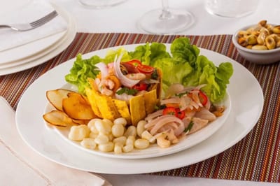 Plate of Panamanian seafood ceviche with shrimp and fish in a fried plantain cup, served with lettuce, hominy corn, and plantain chips