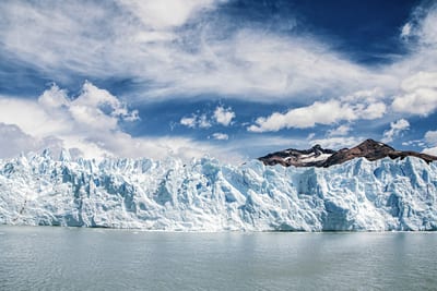 The blue-white face of the Perito Moreno glacier dropping into Lago Argentino in Patagonia, with deep crevasses carved into the ice wall.