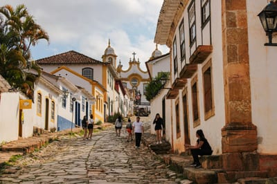 People walk a cobblestone street lined with brightly painted colonial buildings in the Pelourinho historic center of Salvador, Bahia, Brazil.