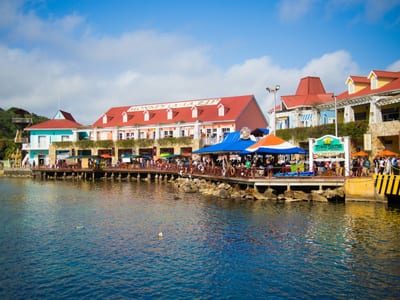 Travelers walking a wooden dock past stilted waterfront houses in West End, Roatán, Honduras.