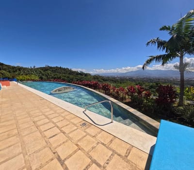 Outdoor pool edged with red ti plants and a palm at Xandari Resort, overlooking the Central Valley and mountains near San José, Costa Rica