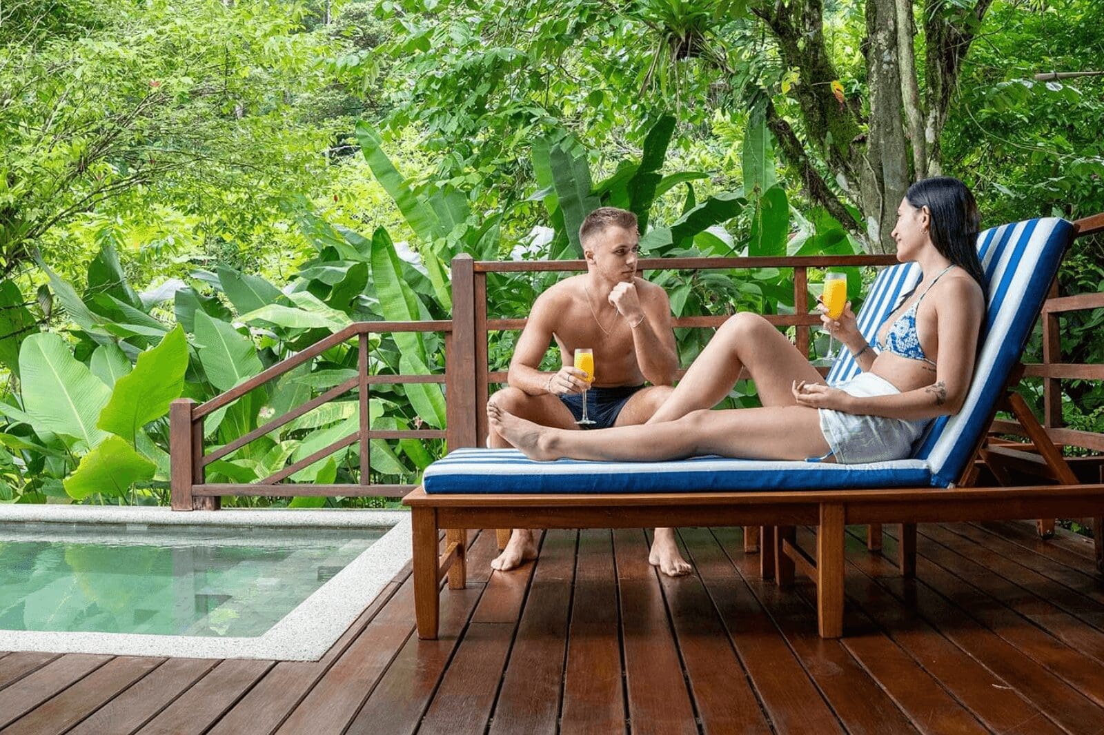 Couple relaxing in front of a pool at an eco-lodge in Costa Rica, surrounded by lush tropical greenery.