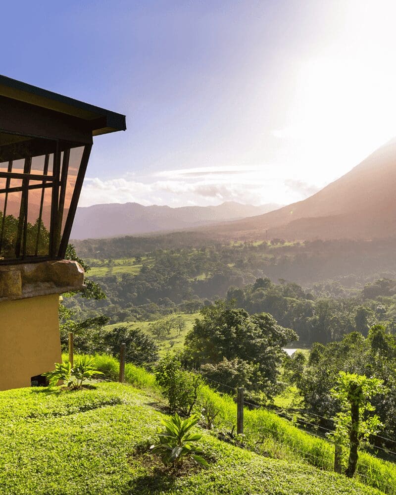 Beautiful midday view of Arenal Volcano with sunlight highlighting the lush green landscape.