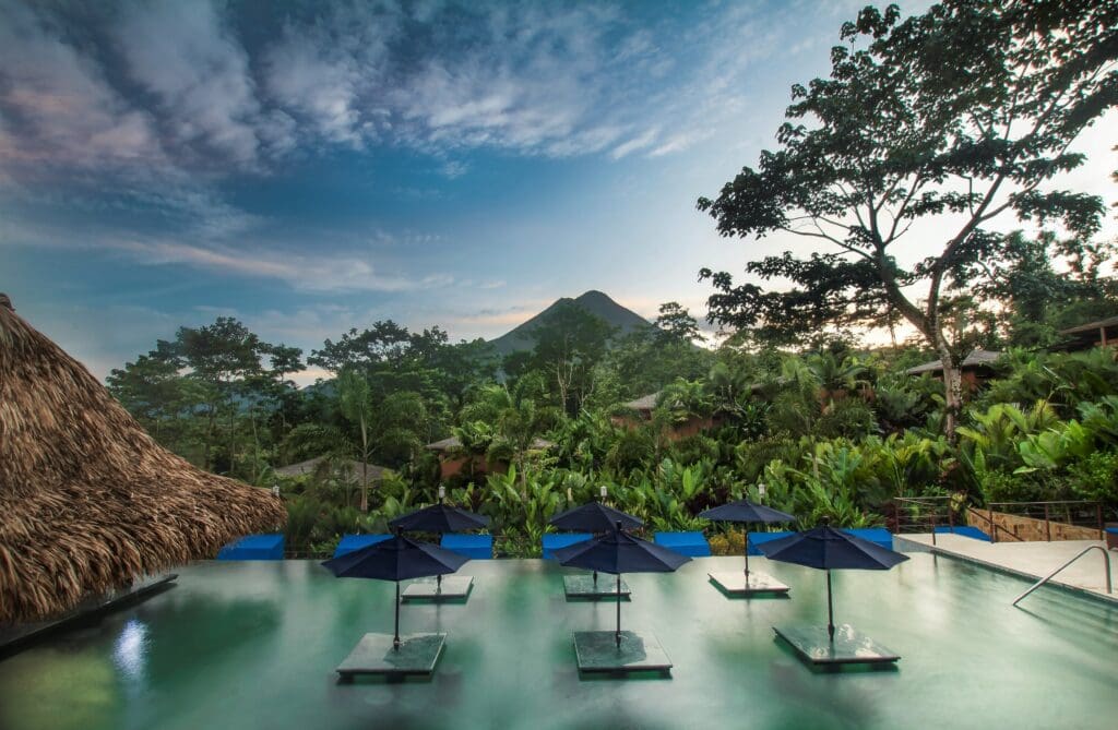 Infinity pool at a luxury rainforest resort in La Fortuna with views of Arenal Volcano surrounded by tropical jungle.