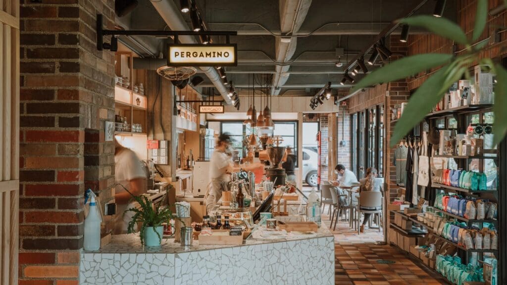 Interior of Pergamino Café in Medellín, with warm lighting, baristas preparing coffee, and shelves filled with locally roasted beans and merchandise.