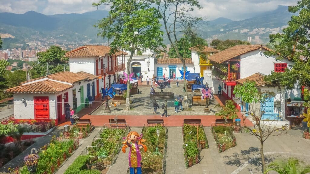 Scenic view of Pueblito Paisa in Medellín, showing traditional Antioquian houses, a central plaza with decorations, and sweeping mountain and city views.